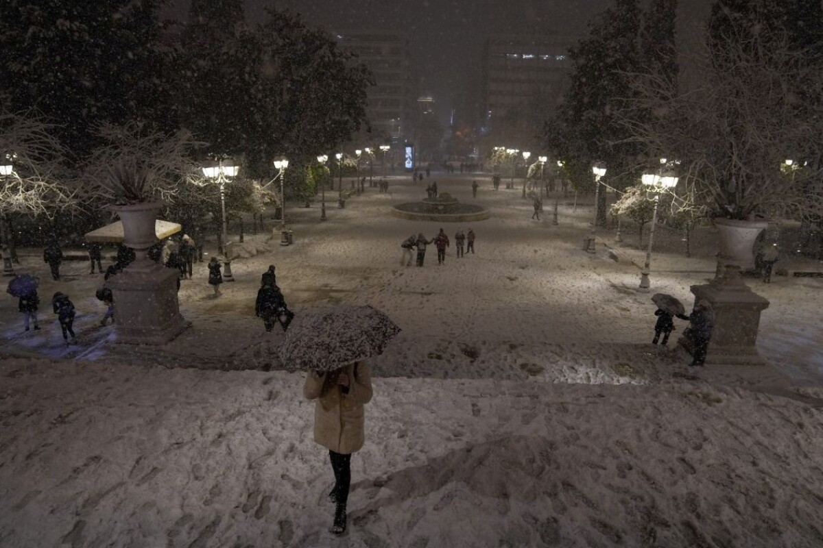 Ľudia kráčajú cez Námestie Syntagma v centre Atén počas hustého sneženia v pondelok 24. januára 2022.