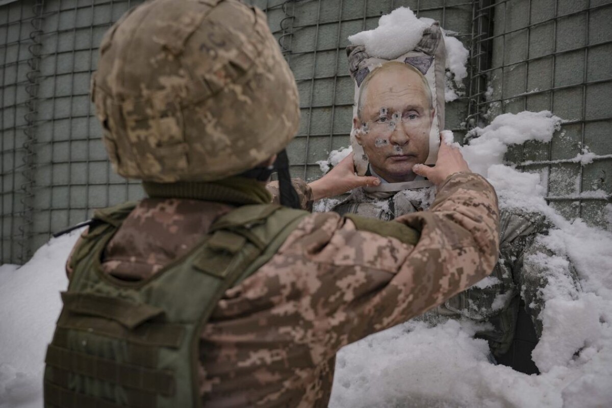 Ukrajinský vojak odstraňuje sneh z rozstrieľanej fotografie ruského prezidenta Putina v Luhanskej oblasti.