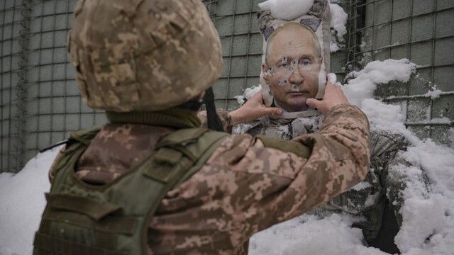Ukrajinský vojak odstraňuje sneh z rozstrieľanej fotografie ruského prezidenta Putina v Luhanskej oblasti.