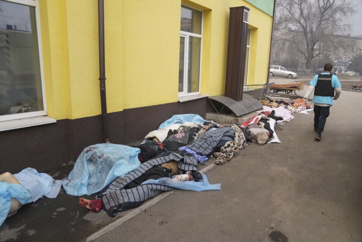 Policajt kráča okolo tiel obetí pred nemocnicou číslo 3, ktoré prišli o život počas ostreľovania v obliehanom meste Mariupol
