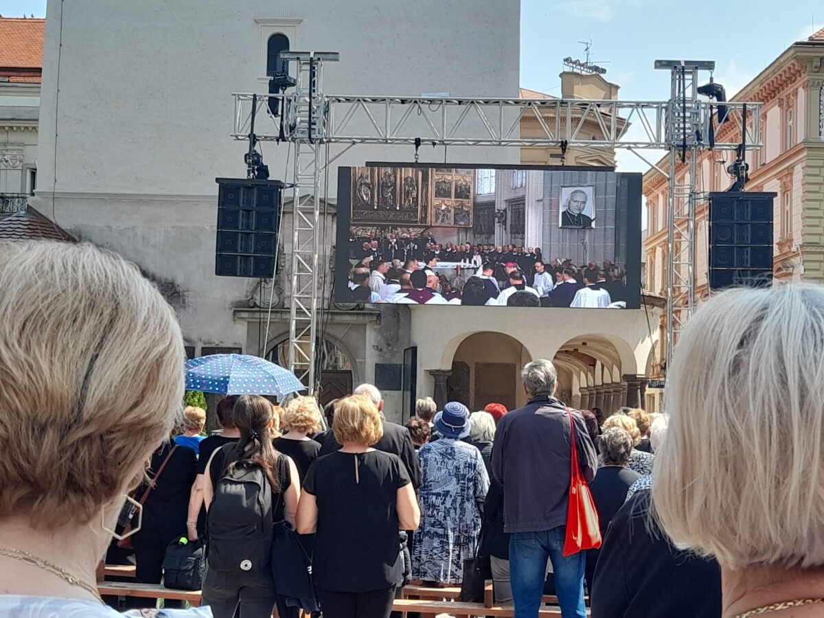 Stovky veriacich, ktorí sa prišli rozlúčiť s emeritným arcibiskupom Alojzom Tkáčom sledujú pohreb na veľkoplošnej obrazovke pri Urbanovej veži v Košiciach.