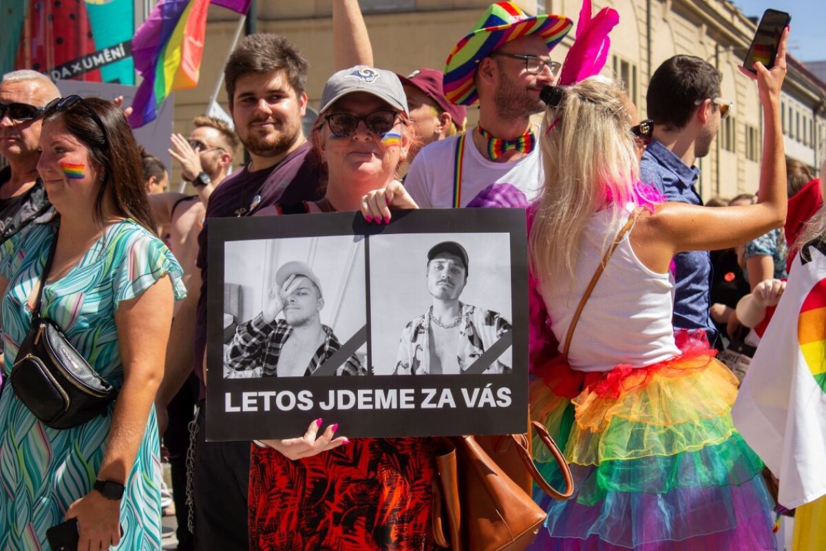 Na snímke účastníčka pochodu homosexuálov Prague Pride drží transparent s fotografiami zavraždených v bratislavskom bare Tepláreň.