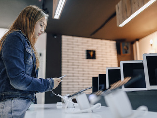 young-attractive-girl-electronics-store-stands-desk-tests-phone.jpg