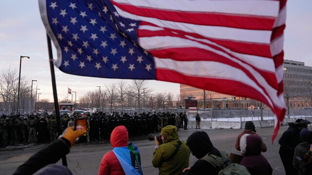 Minnesota protesty Osoba drží prevrátenú americkú vlajku, zatiaľ čo policajti stoja počas protestu pred federálnou budovou biskupa Henryho Whippla v sobotu 17. januára 2026.