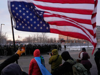 Minnesota protesty Osoba drží prevrátenú americkú vlajku, zatiaľ čo policajti stoja počas protestu pred federálnou budovou biskupa Henryho Whippla v sobotu 17. januára 2026.