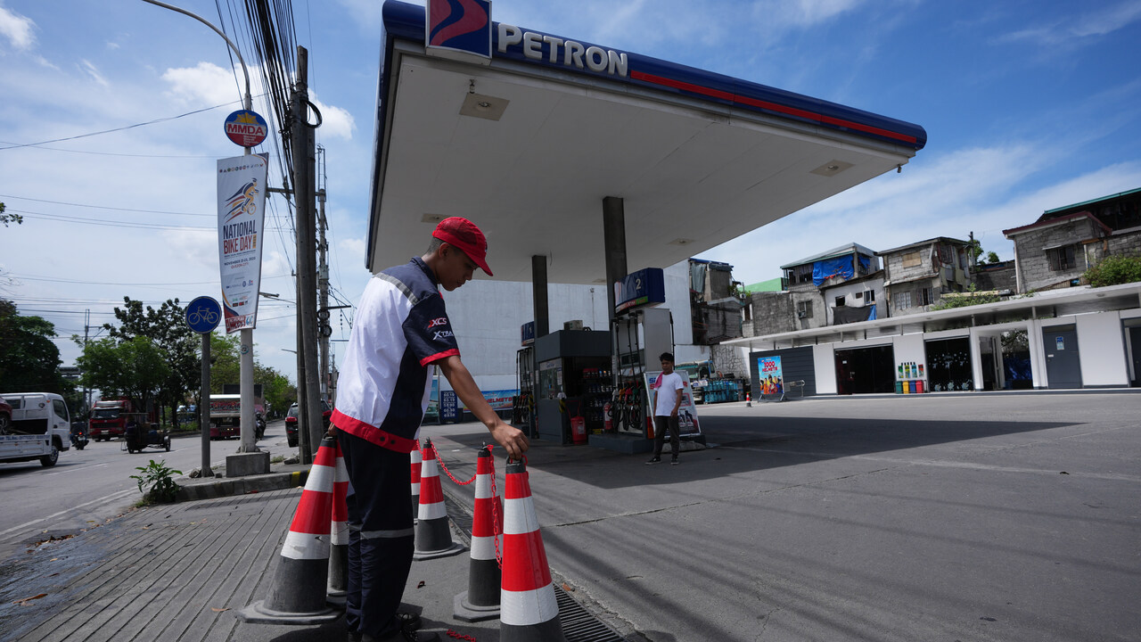 Pracovník umiestňuje kužele na čerpacej stanici, ktorá bola dočasne uzavretá, keď jej došlo palivo, a čaká na novú dodávku, deň pred výrazným zvýšením cien ropy v pondelok 9. marca 2026 v meste Quezon na Filipínach.
