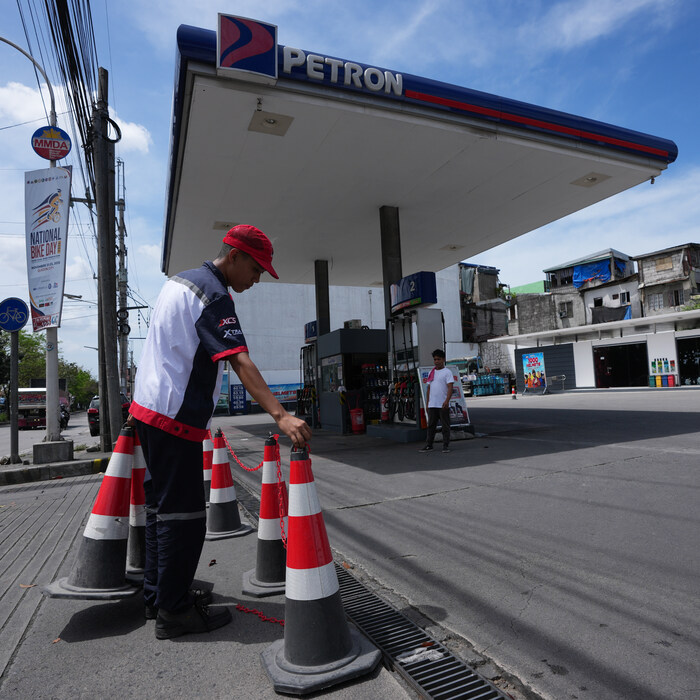 Pracovník umiestňuje kužele na čerpacej stanici, ktorá bola dočasne uzavretá, keď jej došlo palivo, a čaká na novú dodávku, deň pred výrazným zvýšením cien ropy v pondelok 9. marca 2026 v meste Quezon na Filipínach.