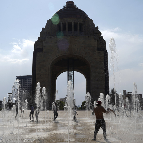 Ľudia sa v utorok 16. apríla 2024 v Mexiku, kde panujú vysoké teploty, zabávajú pri fontáne na úpätí Pamätníka revolúcie. Mexické úrady uviedli, že za nedávny pokles zrážok môžu fenomén El Niño a vlny horúčav.